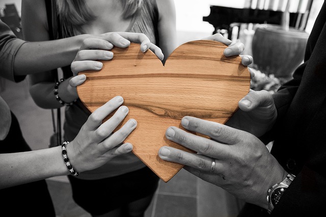 grupa ludzi trzymająca w dłoniach drewniane serce