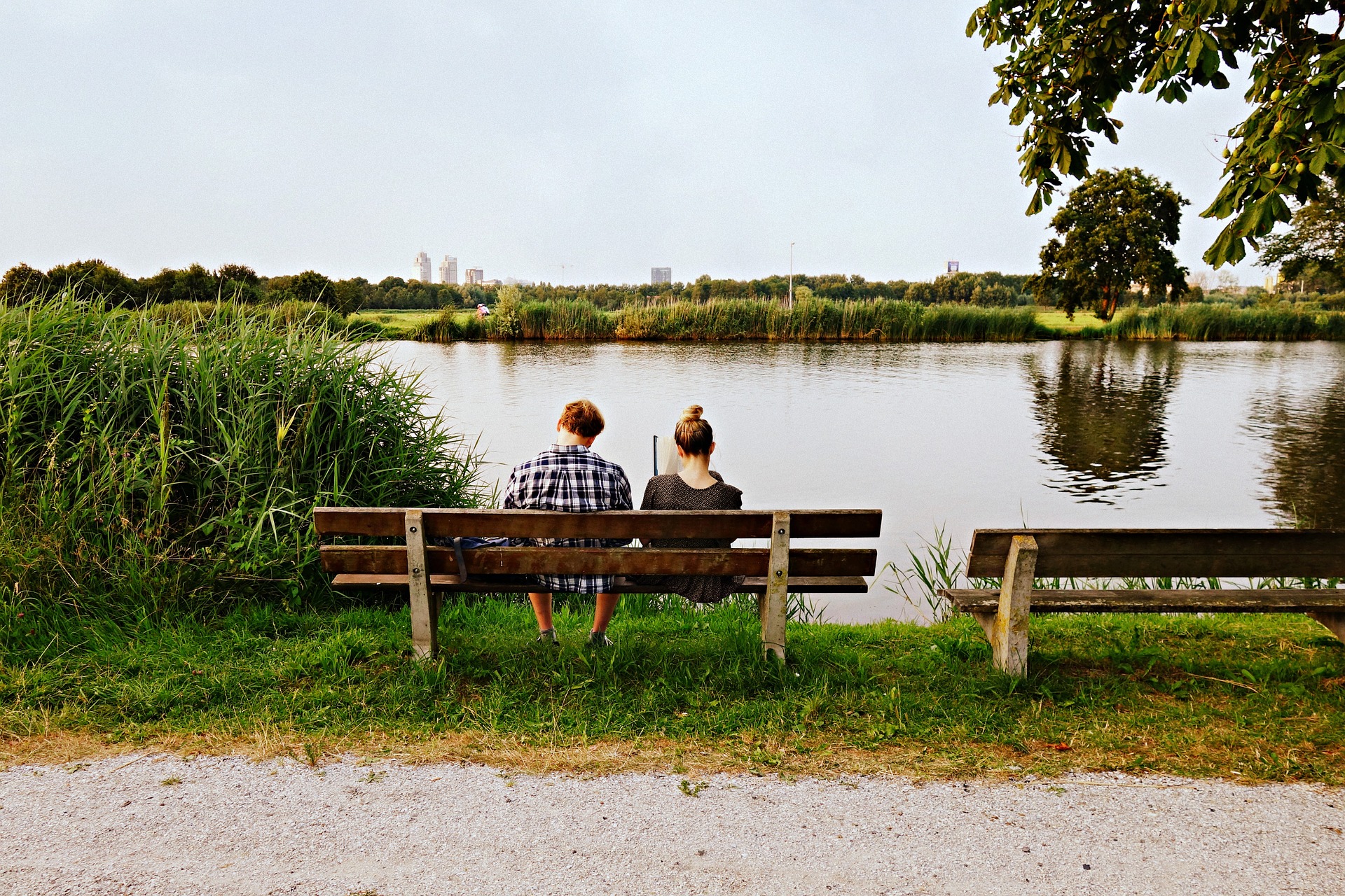 para ludzi siedząca na ławce przed jeziorem