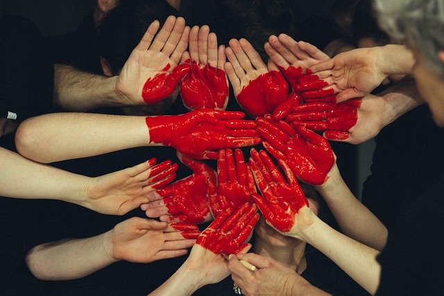 czerwone serce stworzone z dłoni ludzi