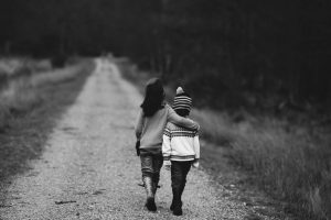 dwójka dzieci idących drogą przytulających się