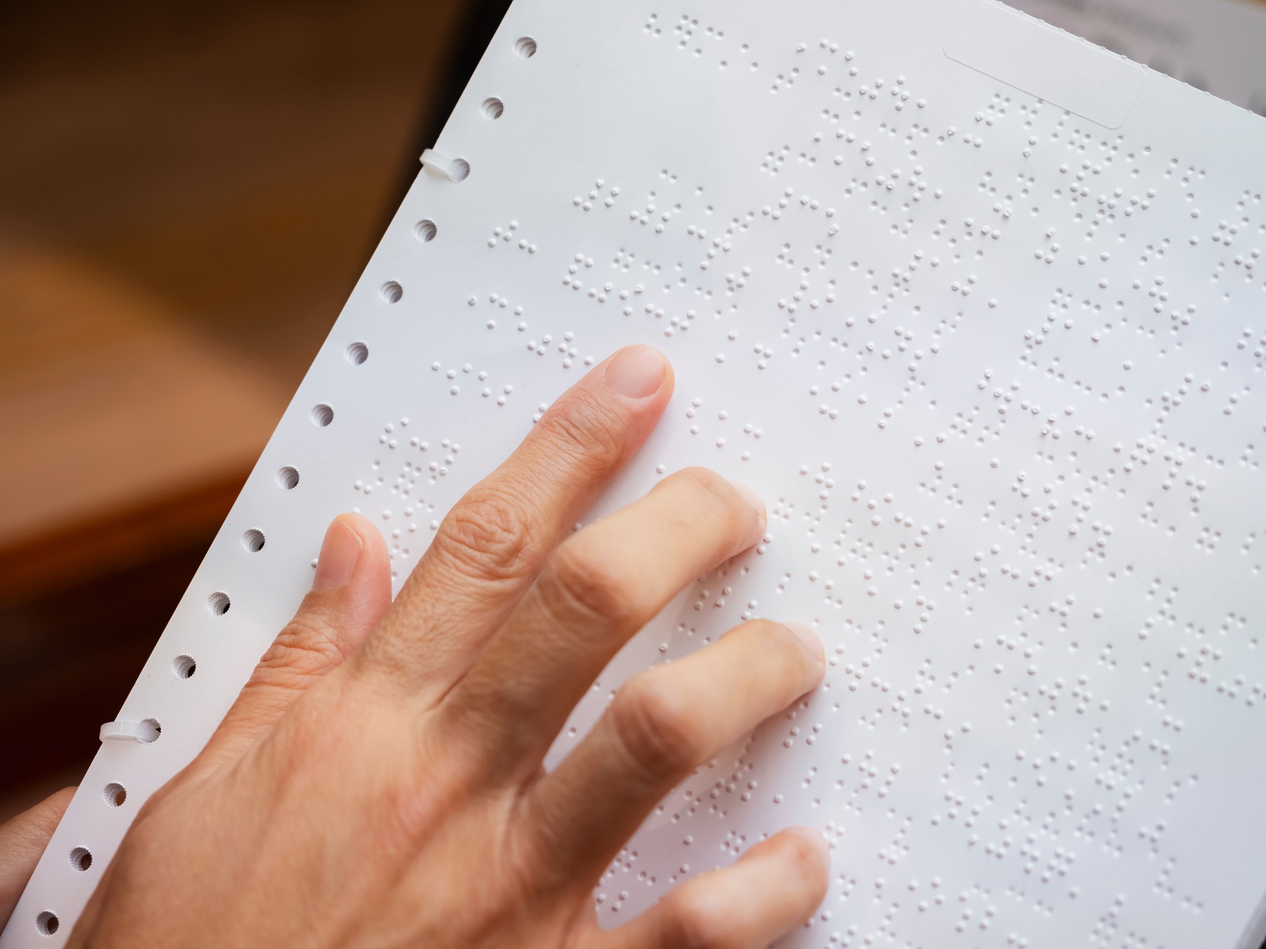 osoba niewidoma czyta tekst palcem napisany językiem braillea