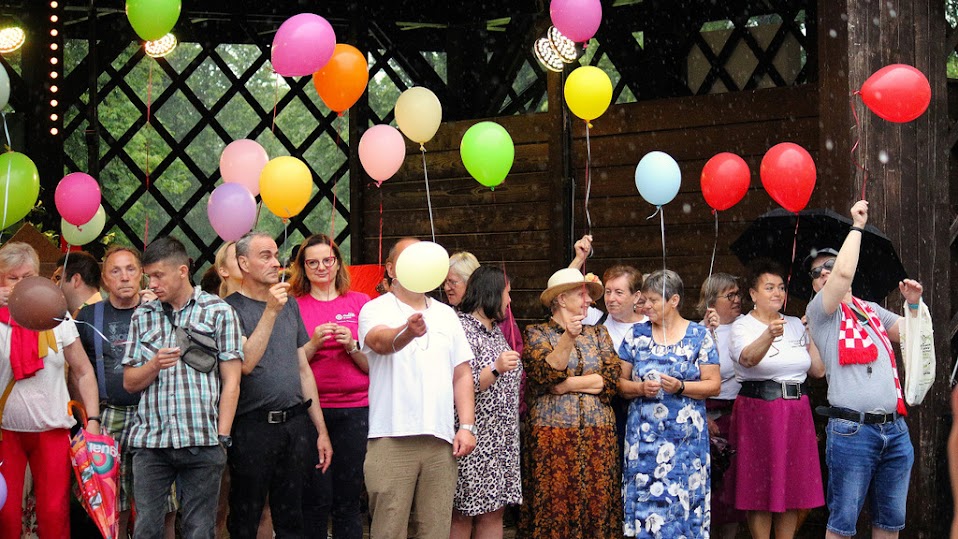 Zdjęcie kilokunastu osób, grupy osób, które trzymają różnokolorowe balony