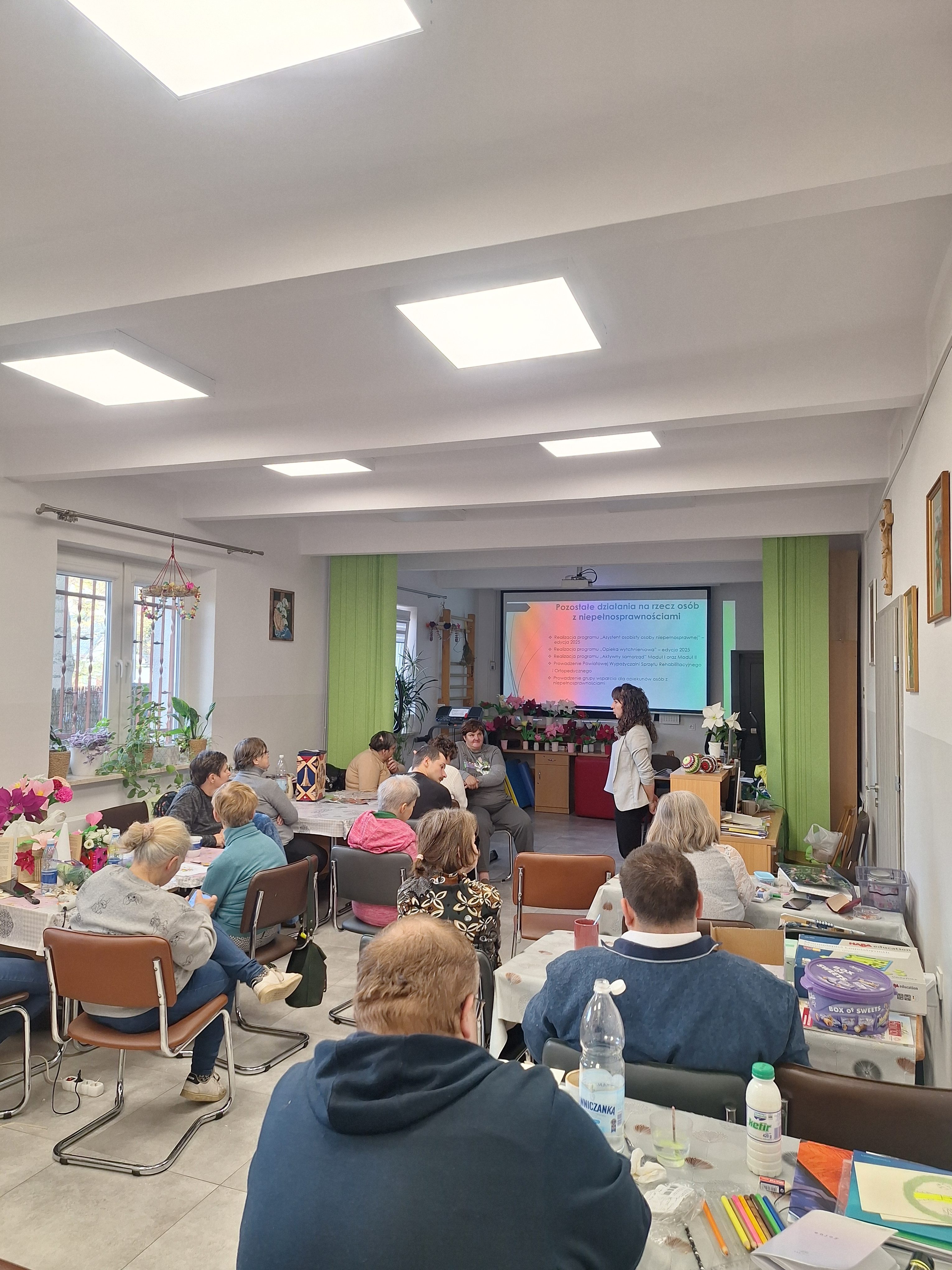 uczestnicy spotkania siedzą w ławkach i słuchają wykładu