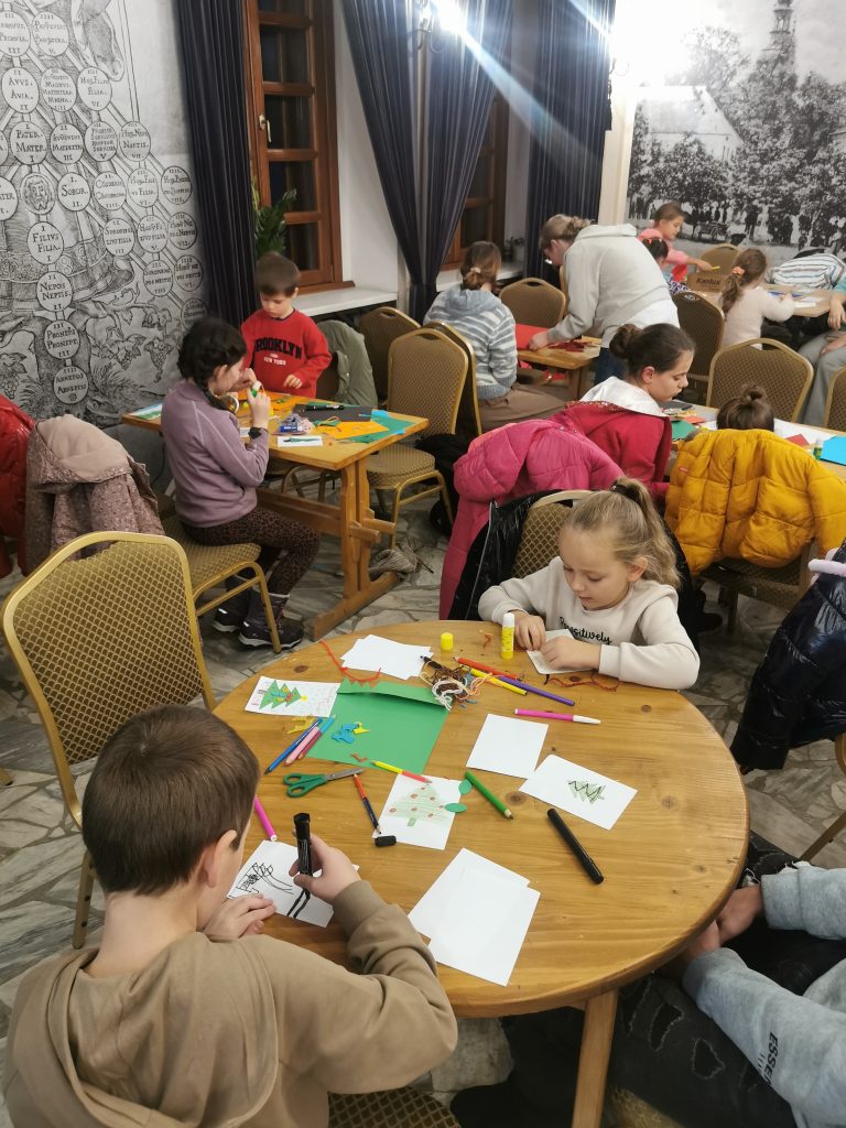 grupa dzieci siedzi wokół stołu i robi prace ręczne