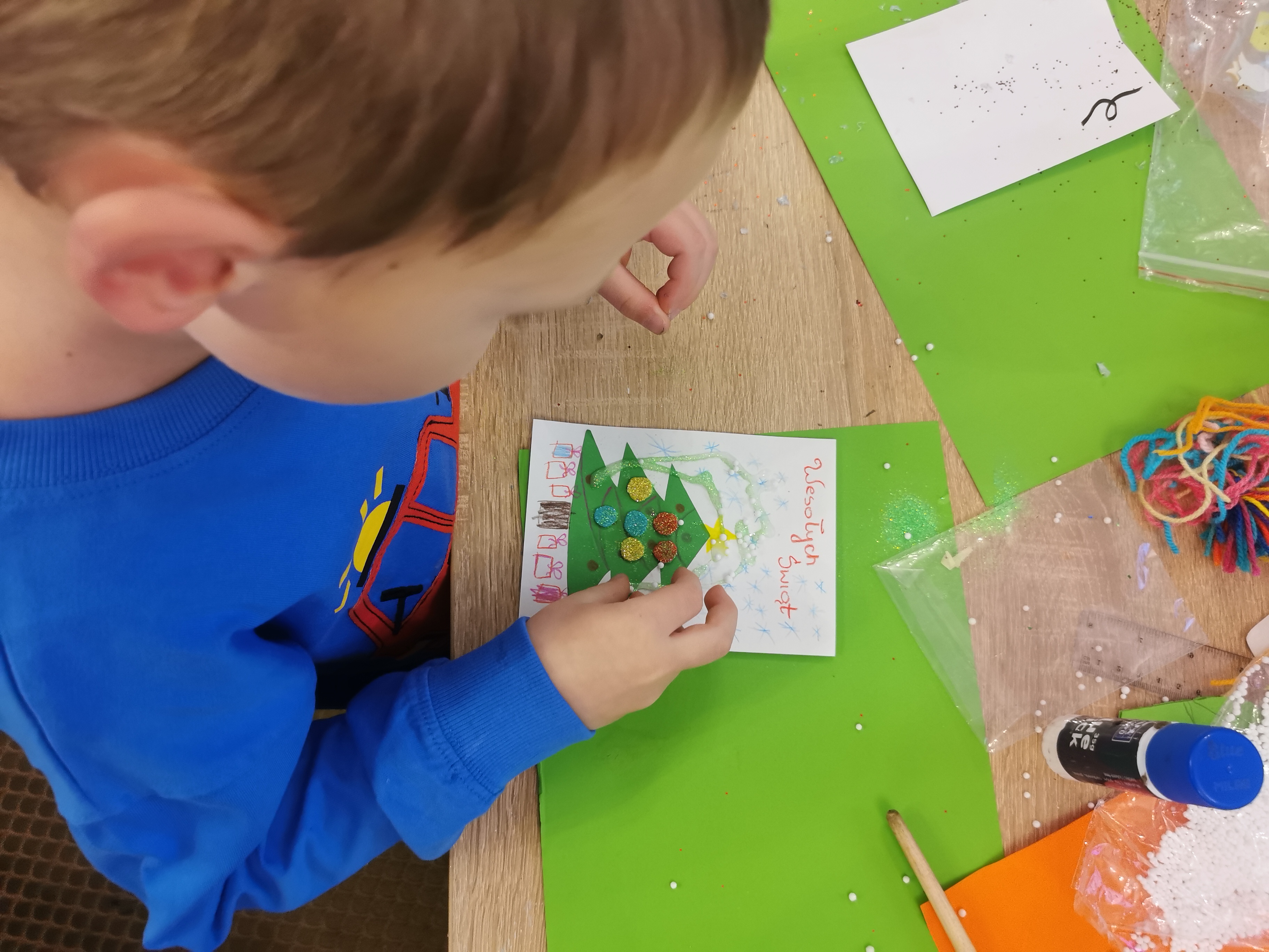 dziecko maluje kartkę pocztową świąteczną