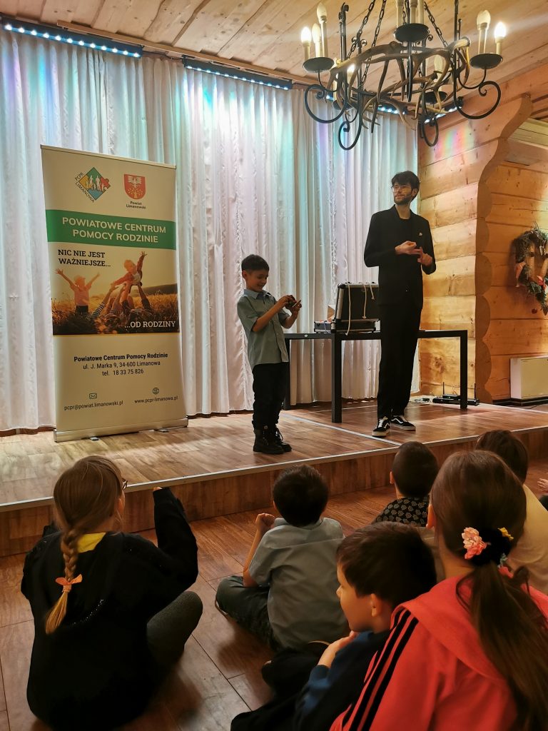 Chłopczyk na scenie próbuje trików magika