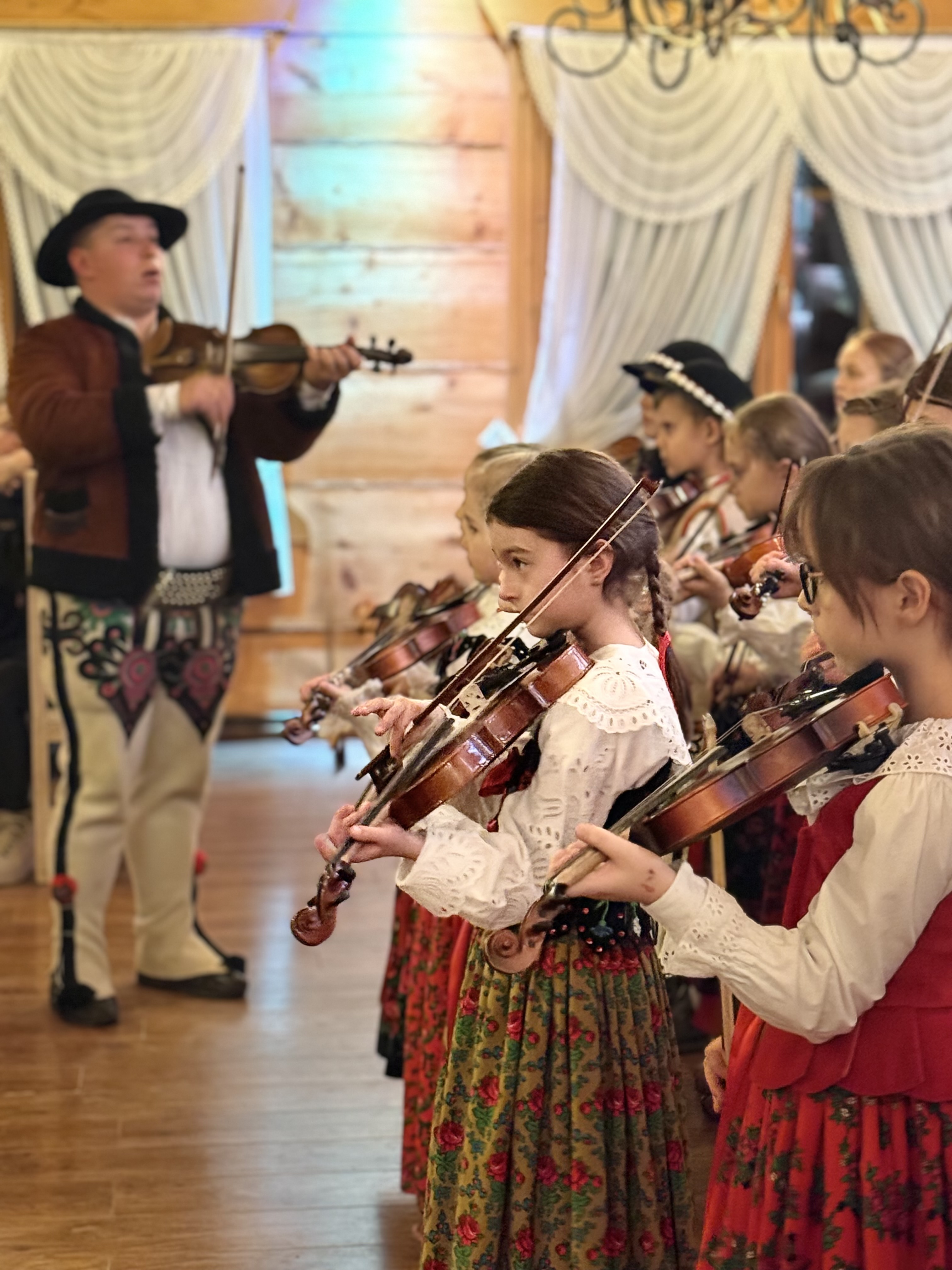 Dzieci ubrane po góralsku grają na skrzypcach
